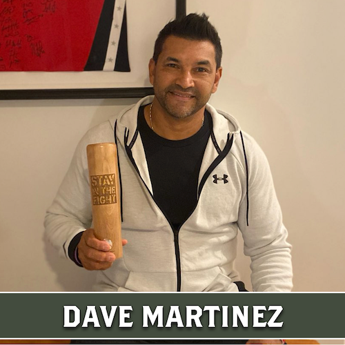 Dave Martinez holding a wooden Dugout Mugs baseball bat mug engraved with "STAY IN THE DUGOUT," with his name displayed in a banner at the bottom.